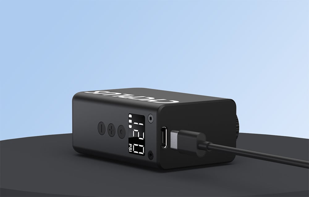 Miniaturowa pompka rowerowa Cycplus podpięta przewodem USB-C do szybkiego ładowania akumulatora.